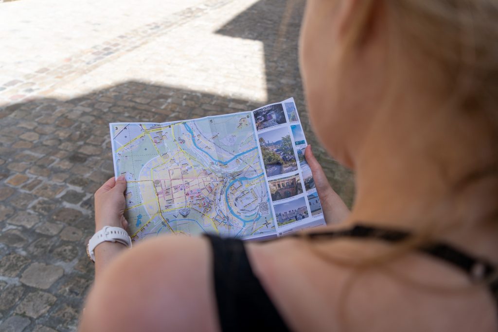 Über die Schulter einer Frau schaut die betrachtende Person auf eine Stadtkarte.